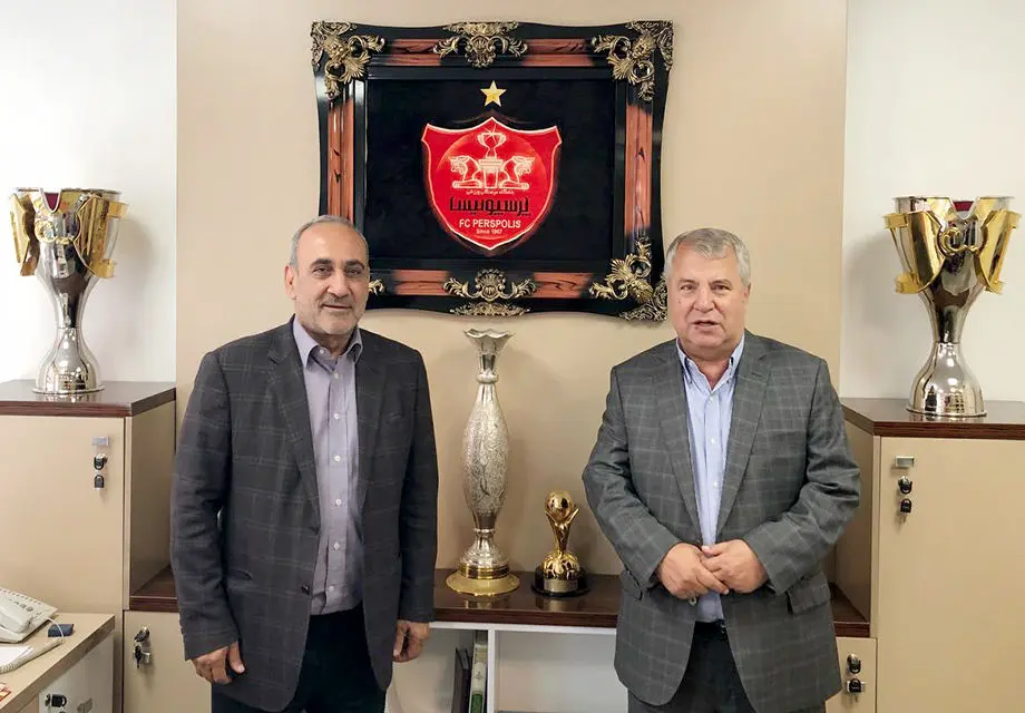علی پروین، جام قهرمانی را روی سکو قرار می‌دهد